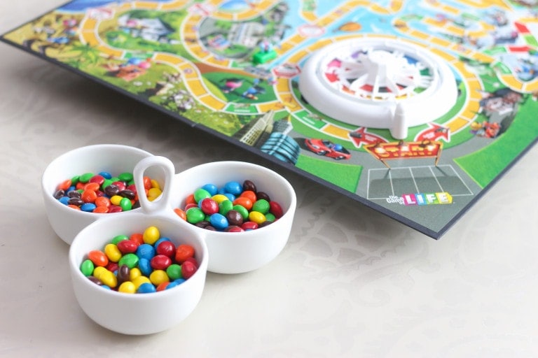Container of M&Ms sitting in front of Life board game sitting on top of a DIY lazy susan