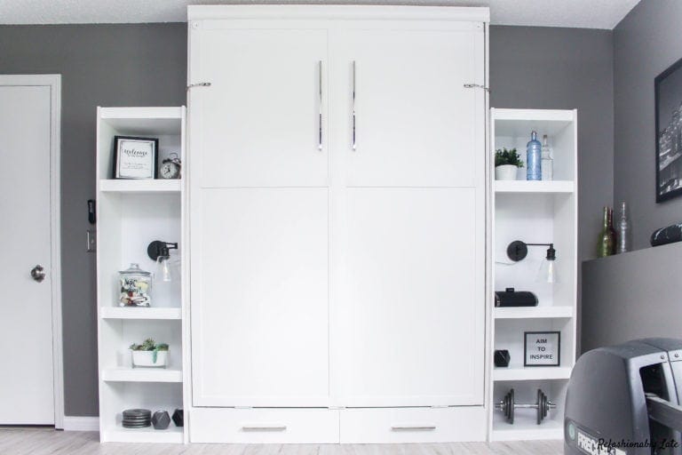 white murphy bed with two shelves on either side with decorative items against a dark gray wall and white maple allure grip strip vinyl flooring