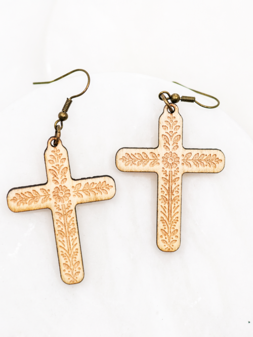 Wood cross dangle earrings with engraved floral detail and gold hooks, photographed on a clean white background.