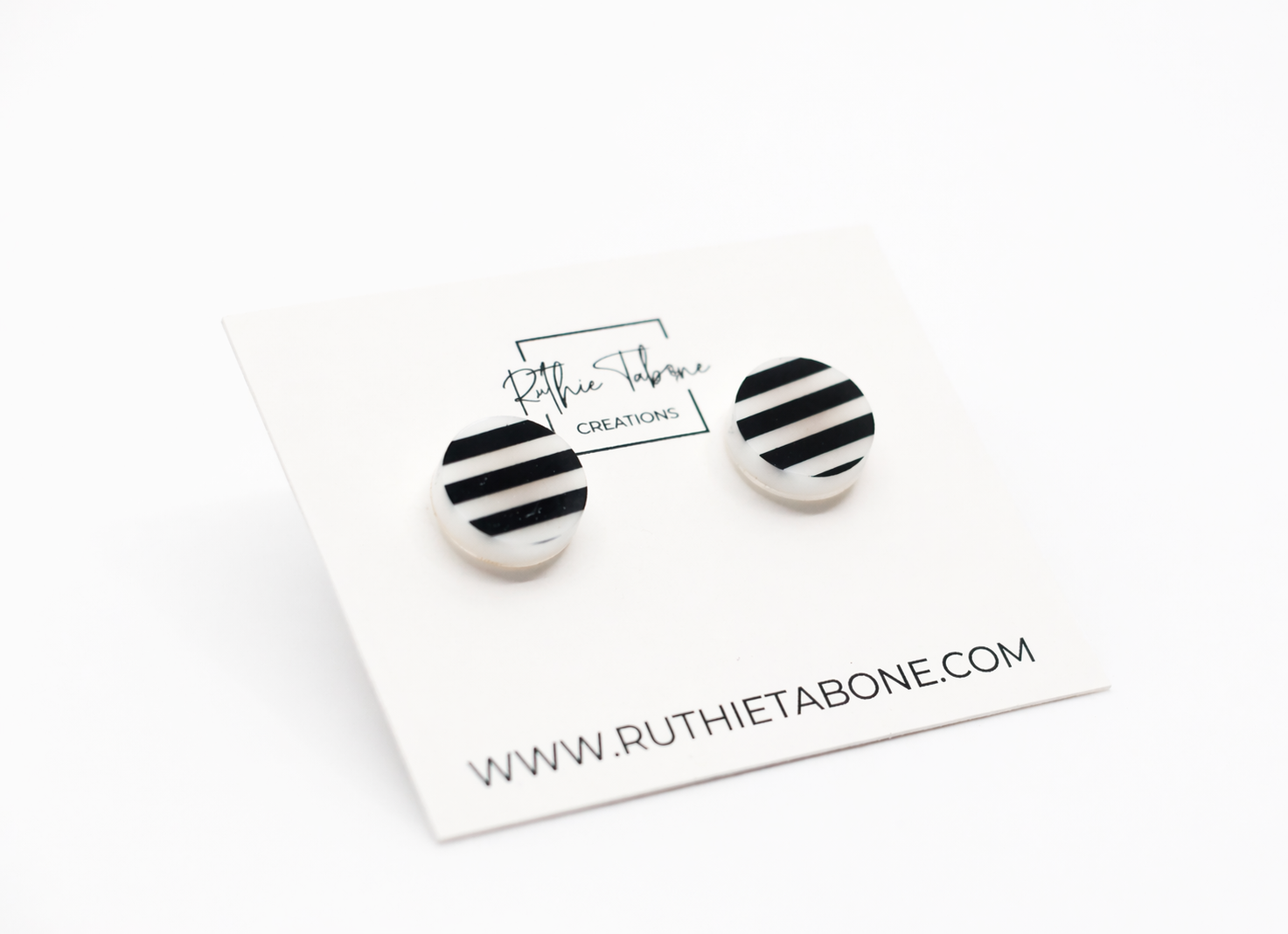 Black and white striped round stud earrings displayed on a Ruthie Tabone Creations card, shown at a slight angle on a clean white background.