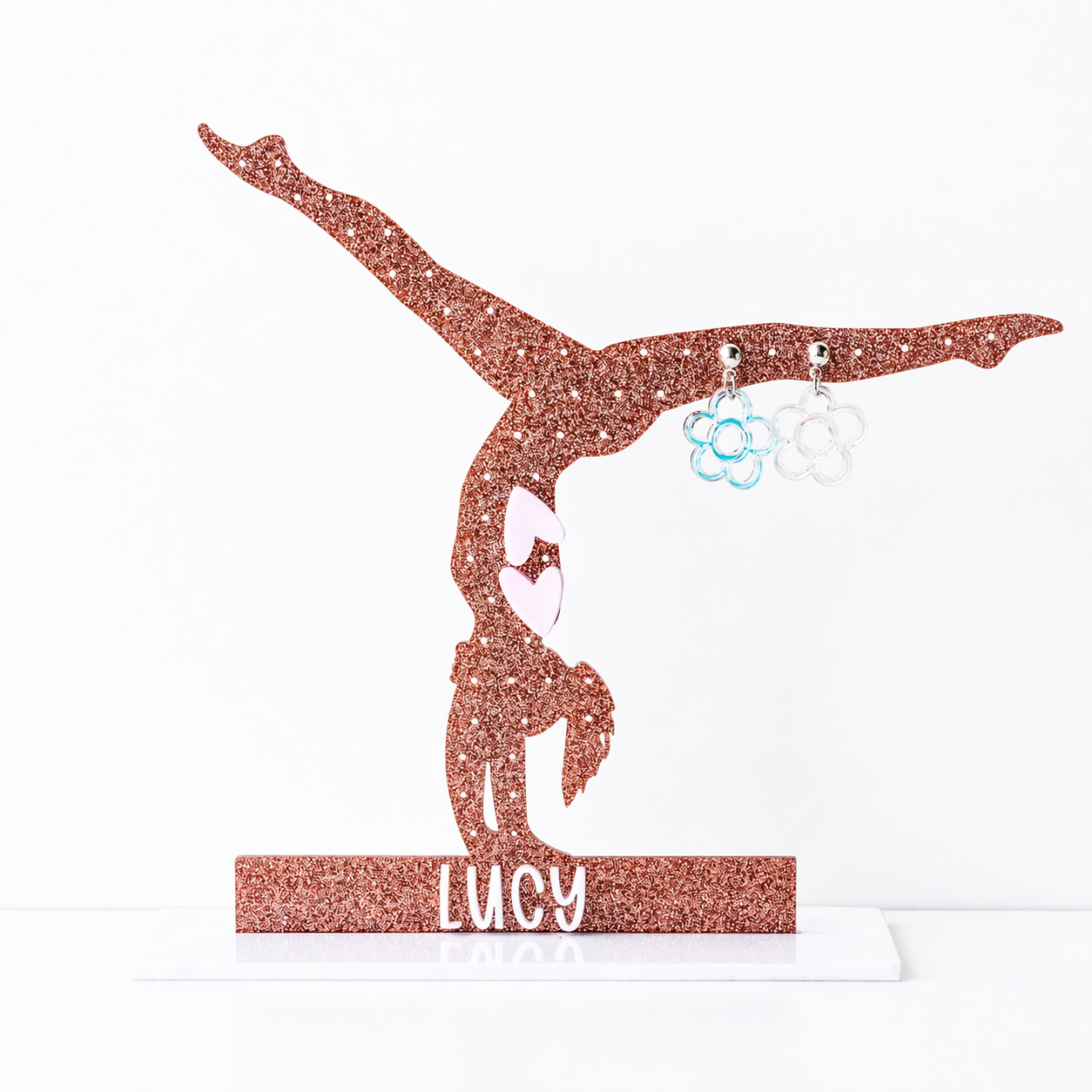 Glitter gymnast silhouette earring holder personalized with the name “Lucy,” displaying small flower stud earrings against a clean white background.