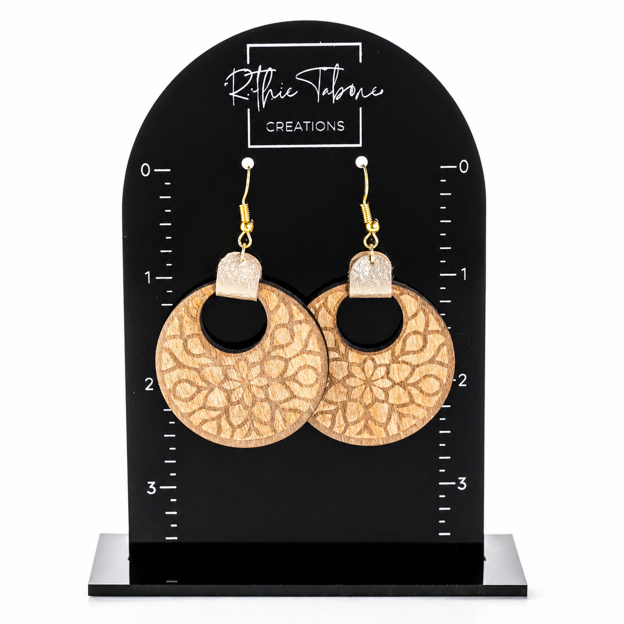 Wood mandala earrings with engraved floral design and gold hooks on black measurement display