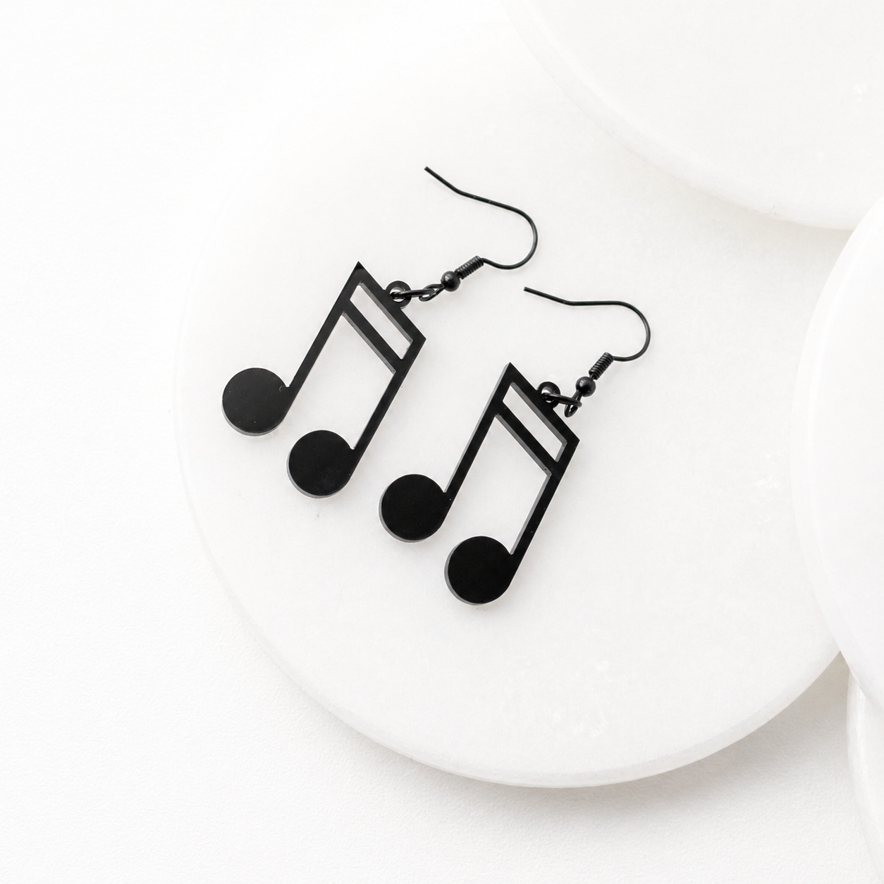 Black music note dangle earrings with stainless steel hooks on a white display