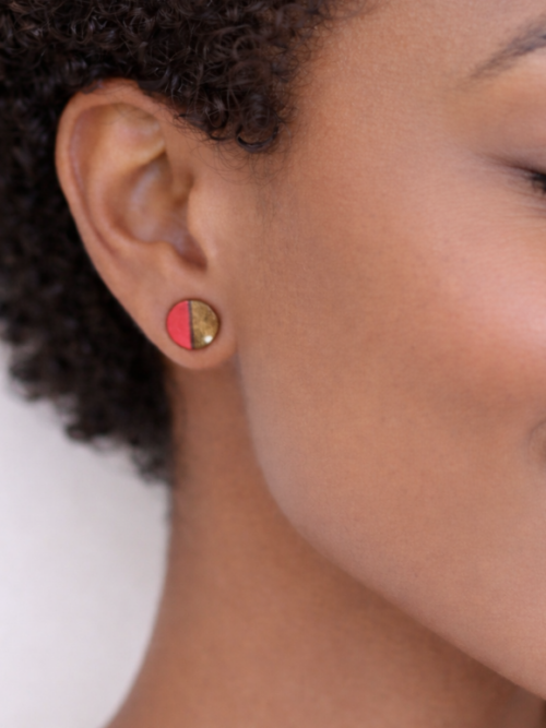 Close-up of a model wearing handmade round pink and natural wood stud earrings by Ruthie Tabone Creations.