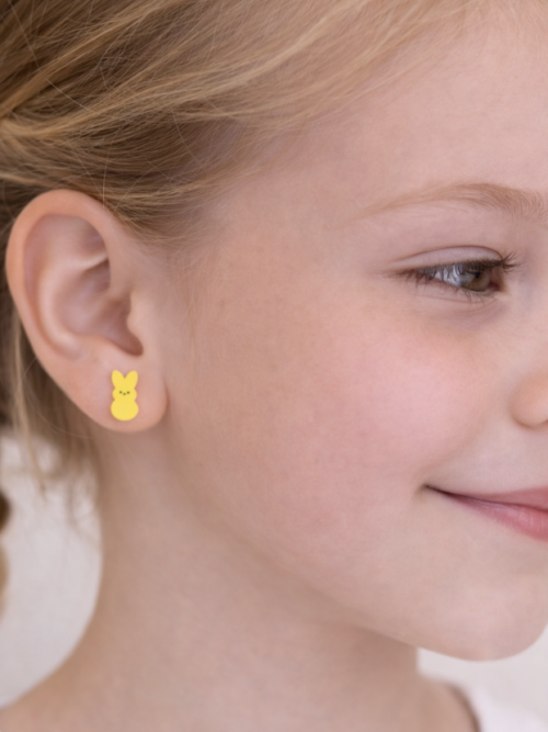 Child wearing yellow bunny stud earrings, shown in a close-up side profile with braided hair and a soft, natural background.