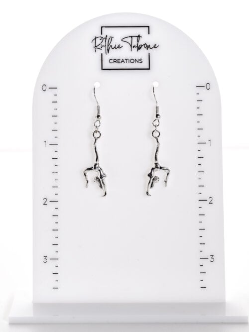 Silver gymnast dangle earrings in a graceful handstand pose, displayed on a Ruthie Tabone Creations measuring stand to showcase length and movement, styled with a clean, modern aesthetic.