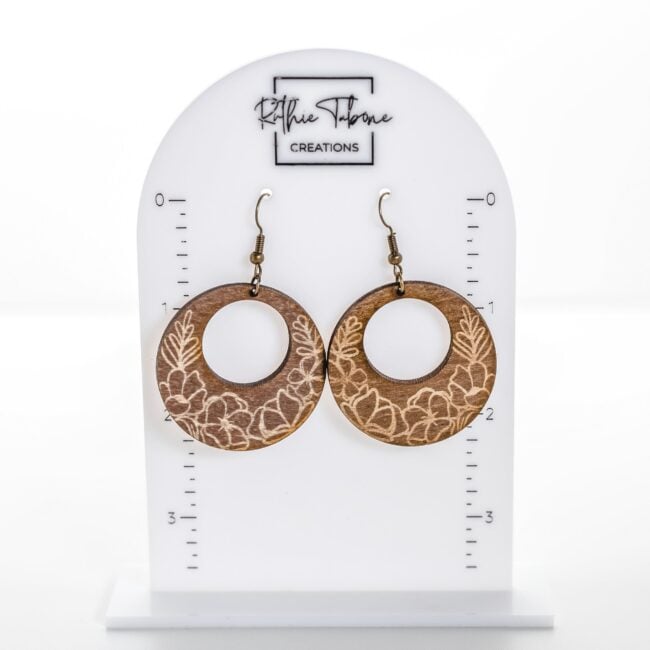 Handmade engraved wood hoop earrings with floral design and gold hooks by Ruthie Tabone Creations displayed on white jewelry card.