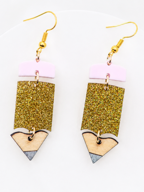 Handmade pencil dangle earrings with pink acrylic erasers, sparkling gold glitter centers, natural wood pencil tips, and gold hooks.