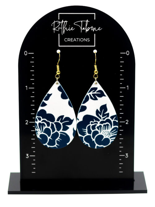 Navy blue floral teardrop dangle earrings displayed on a branded earring stand, featuring a crisp white background and gold hooks—lightweight, elegant, and perfect for adding a classic pop of pattern to any outfit.