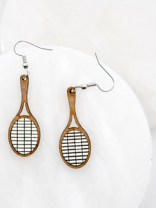 Wood racket dangle earrings with white and black string detail and silver hooks, displayed on a clean white background.