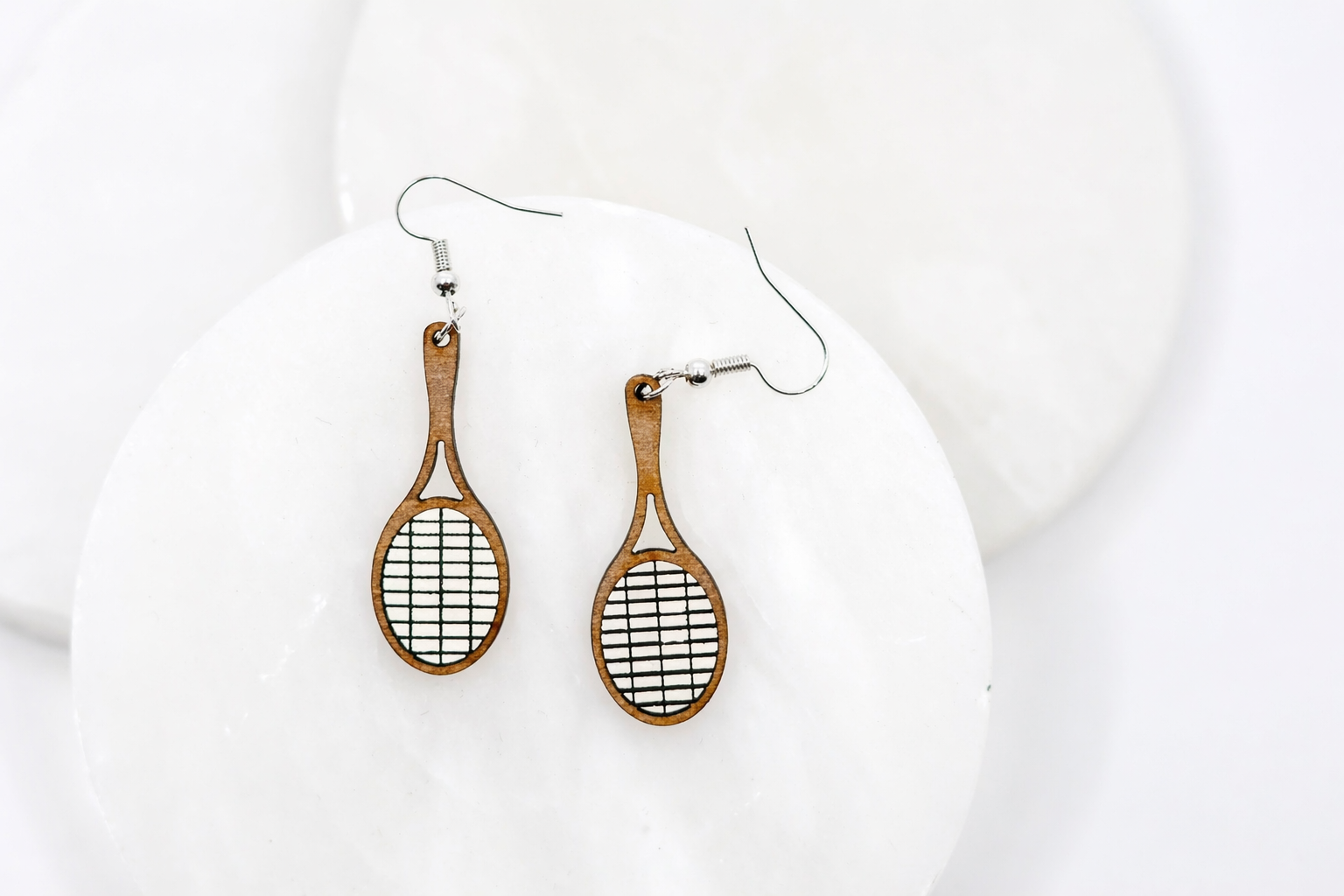 Wood racket dangle earrings with white and black string detail and silver hooks, displayed on a clean white background.