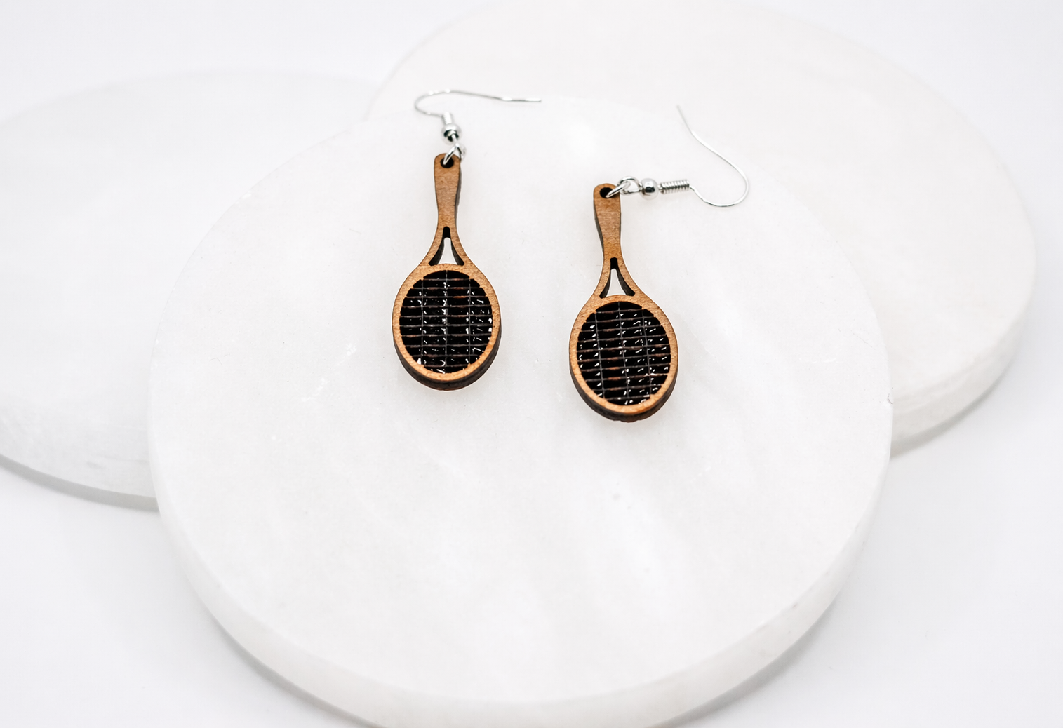 Wood racket dangle earrings with black string detail and silver hooks, displayed on a clean white background.