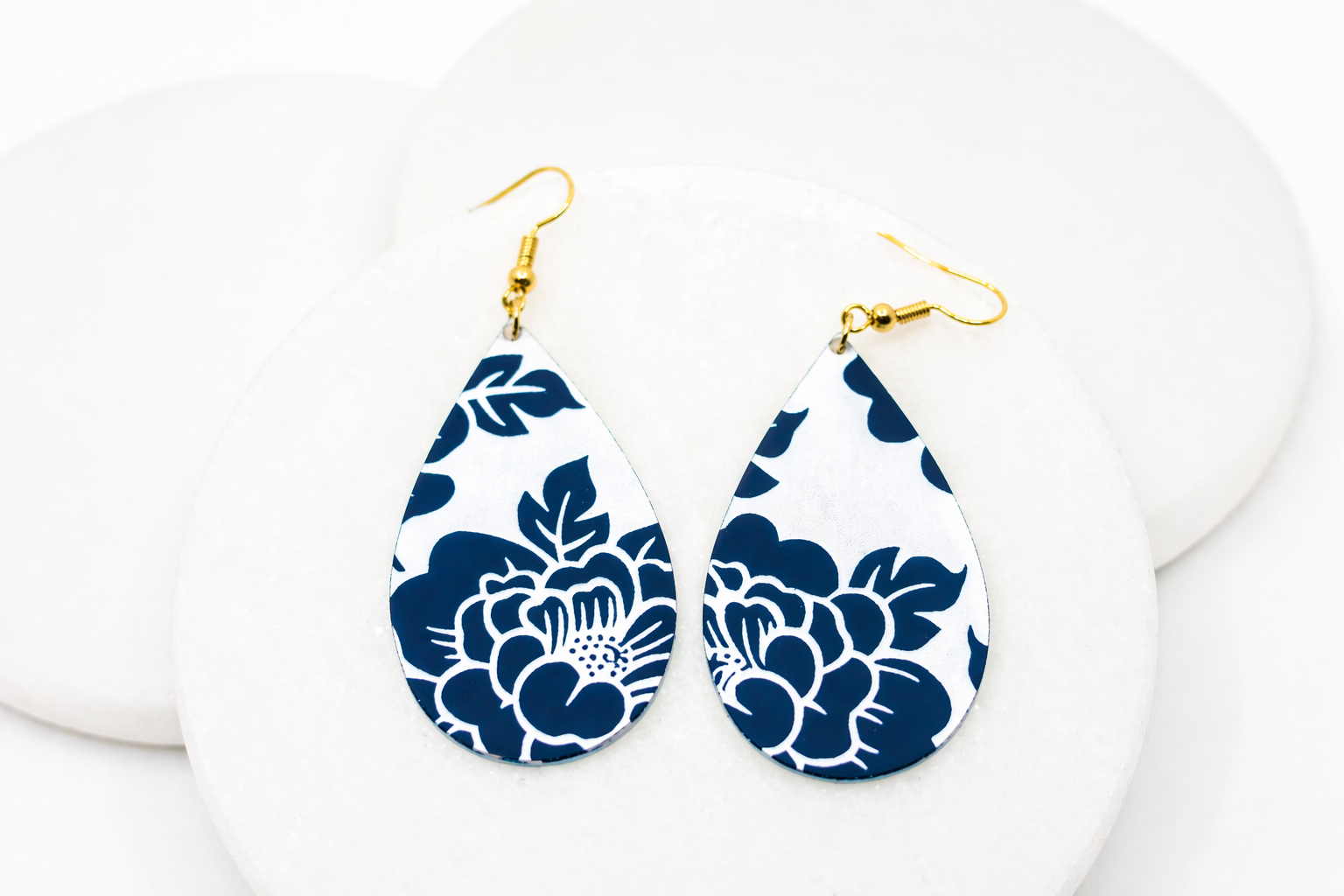 Navy blue floral teardrop earrings with a crisp white background and gold hooksβlightweight, timeless, and perfect for adding a bold yet classic touch to any outfit.