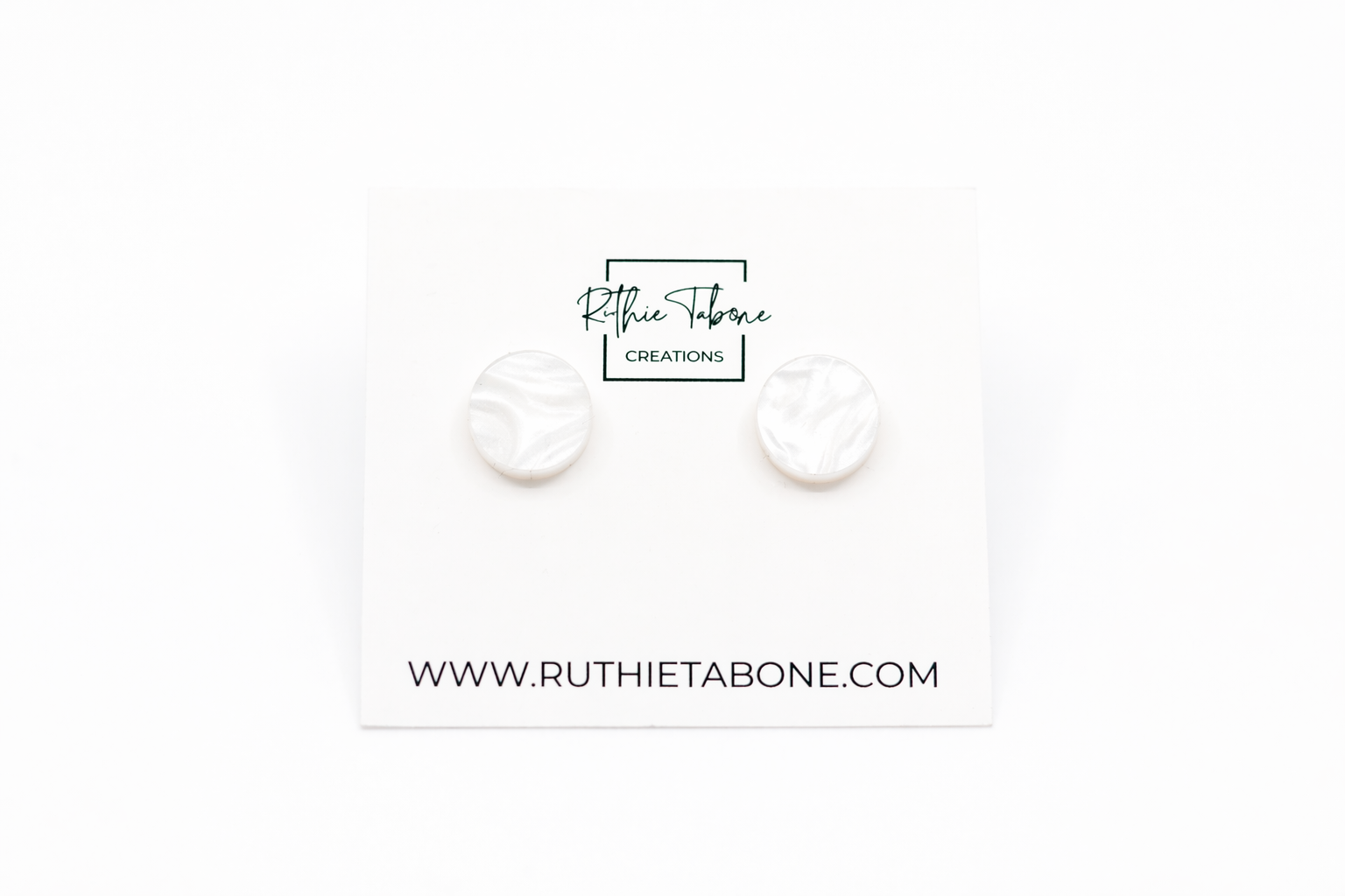 White marbled round stud earrings with subtle shimmer, displayed on a Ruthie Tabone Creations card against a clean white background.