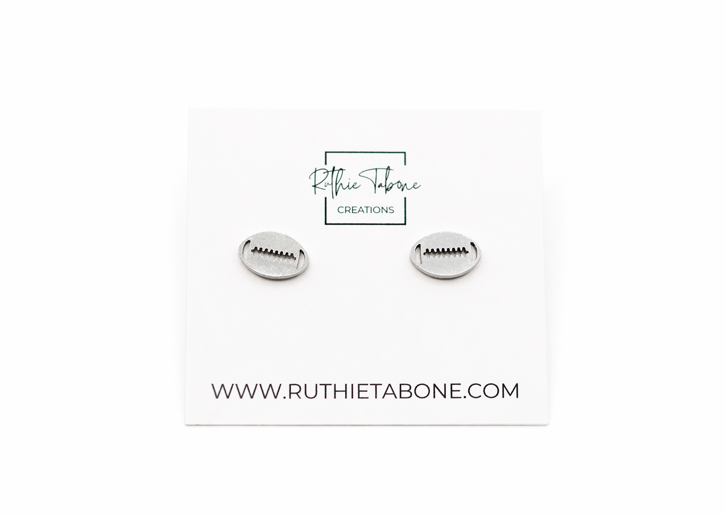 Silver football stud earrings with engraved lace detail displayed on a Ruthie Tabone Creations card against a clean white background.