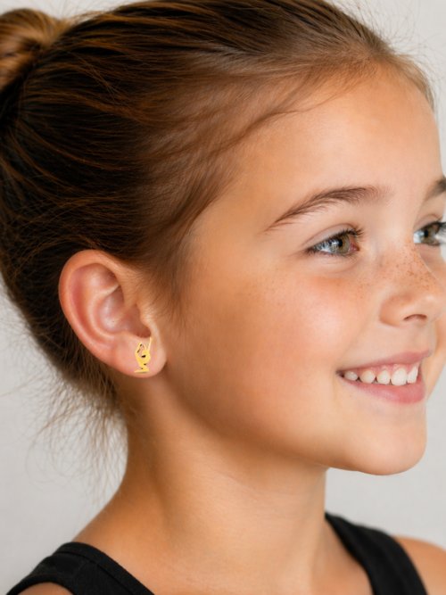 Smiling young girl with hair in a bun wearing small gold gymnast silhouette stud earrings, shown in a side profile against a neutral background.