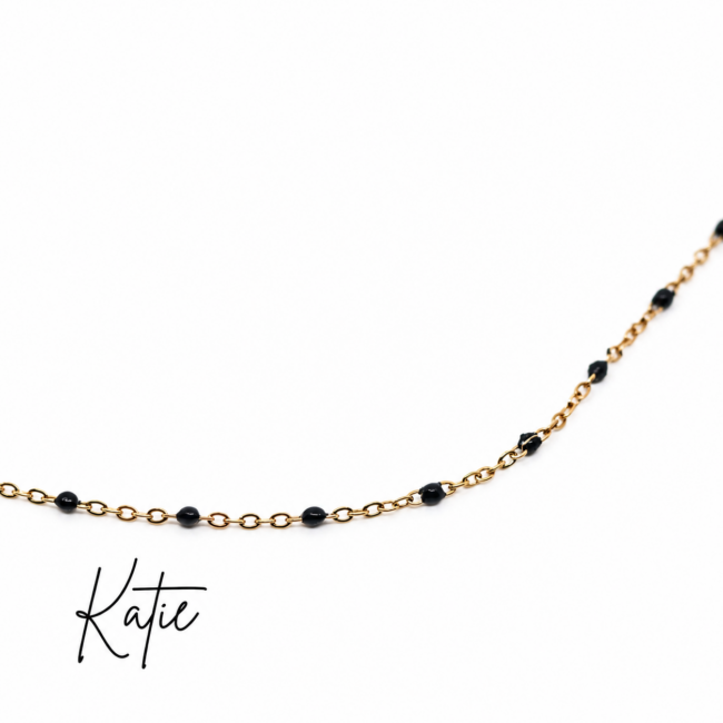 Close-up of a delicate gold chain necklace featuring evenly spaced small black beads, displayed against a clean white background. The minimalist beaded design offers a timeless, everyday look that can be worn alone or layered with other necklaces.