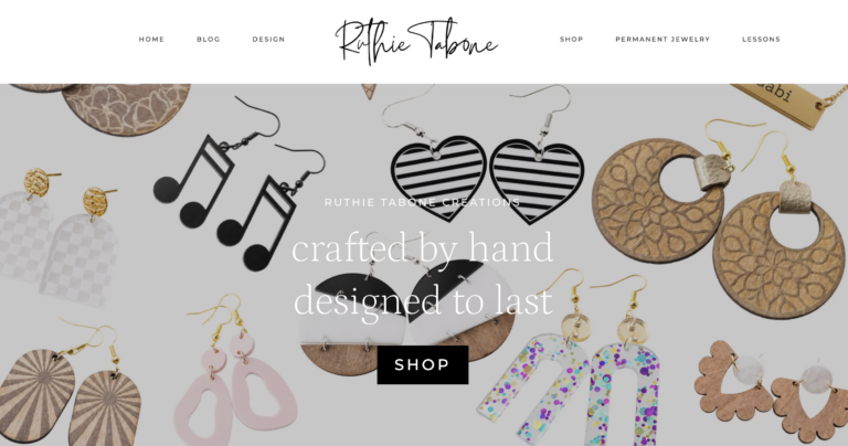 Homepage banner for Ruthie Tabone Creations featuring a collection of handmade hypoallergenic earrings, including wood, acrylic, music note, heart, floral, striped, and colorful glitter designs, surrounding the text "Crafted by hand, designed to last" with a Shop button. The navigation includes Home, Blog, Design, Shop, Permanent Jewelry, and Lessons.